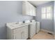 Bright laundry room with white cabinets, sink, washer, and dryer under a window with shuttered blinds at 562 Grassmeade Way, Snellville, GA 30078