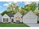 Charming home with white stone facade, black roof, manicured lawn, and bright, sunny skies at 290 Magnolia Walk Ln, Atlanta, GA 30349
