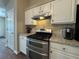 Modern kitchen with stainless steel gas range, granite countertops, tile backsplash, and custom cabinetry at 5668 Blanchard Pl, Sugar Hill, GA 30518