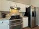 Close up of kitchen features, including stainless steel range, granite countertops, tile backsplash, and white cabinets at 5668 Blanchard Pl, Sugar Hill, GA 30518