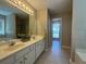Bright bathroom featuring dual sinks, a soaking tub, and tile floors, creating a spa-like retreat at 5668 Blanchard Pl, Sugar Hill, GA 30518