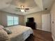 Comfortable main bedroom featuring dark wood floors, a trey ceiling, ceiling fan, and a television at 5668 Blanchard Pl, Sugar Hill, GA 30518