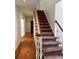 Hallway featuring a carpeted staircase, wood flooring, and neutral paint at 9290 Prestwick Club Dr, Johns Creek, GA 30097