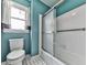 Bathroom featuring a white tiled shower with a sliding door, and a toilet beside a window at 140 N Lakeside Nw Dr, Kennesaw, GA 30144