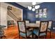 Elegant dining room with blue accent wall, modern lighting, and a hardwood staircase in view at 2250 W Village Junction Se Way, Smyrna, GA 30080