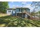 Landscaped backyard with wooden deck/stairs, lush lawn, and mature trees at 3015 Larkspur Ct, Cumming, GA 30041