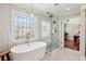 Bright bathroom with a soaking tub, glass shower, decorative window, and access to the main bedroom at 4765 Karls Gate Dr, Marietta, GA 30068