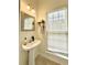 Bathroom featuring a pedestal sink, decorative mirror and sconces, and a bright window at 5401 Fox Creek Lane, Norcross, GA 30071