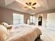 Spacious primary bedroom featuring tray ceiling, fan, and adjoining walk-in closet at 5401 Fox Creek Lane, Norcross, GA 30071