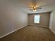 A neutral bedroom features carpet, a ceiling fan, and a window that lets in natural light at 5820 Wellborn Oaks Ct, Lithonia, GA 30058