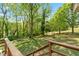View from the back deck, showcasing a serene, tree-lined backyard with a beautiful green lawn and an outdoor fire pit at 645 Camp Perrin Rd, Lawrenceville, GA 30043