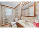 A traditional bathroom featuring floral wallpaper, a window, a vanity with countertop, and a toilet at 645 Camp Perrin Rd, Lawrenceville, GA 30043
