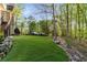 Spacious backyard featuring lush green lawn, mature trees, and natural stone landscaping at 6050 Providence Ln, Cumming, GA 30040