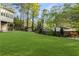 Large backyard with a greenhouse, storage shed, mature trees, and a lush green lawn at 6050 Providence Ln, Cumming, GA 30040