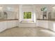 Elegant main bathroom features double vanities, soaking tub under a window, and tiled floor at 6050 Providence Ln, Cumming, GA 30040