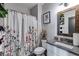 Bathroom with modern floral shower curtain, toilet, vanity, and decorative mirror with black and wood accents at 7001 Palomino Trl, Winston, GA 30187
