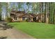Beautiful brick home with green lawn, mature trees, and a paved driveway leading to the property at 11815 Mountain Laurel Dr, Roswell, GA 30075