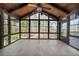 Bright sunroom with tile flooring, wood paneled ceiling, and expansive windows with a view of the trees at 11815 Mountain Laurel Dr, Roswell, GA 30075