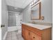 Bathroom featuring a shower, marble sink, and a wooden framed mirror with a silver faucet and gray tiling at 3311 Lost Meadows Ln, Buford, GA 30519