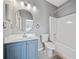 Bathroom featuring blue vanity, mirror, toilet, and shower-tub combination at 419 Farmwood Way, Canton, GA 30115