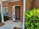 Close-up of the condo's front door, with a trimmed green bush in front of the red-brick facade at 101 Spring Heights Se Ln # 1, Smyrna, GA 30080