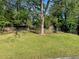 Grassy backyard featuring mature trees, a partial fence, a shed and a treehouse at 566 Huff St, Lawrenceville, GA 30046