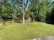 Grassy backyard featuring mature trees, a partial fence, and an outbuilding at 566 Huff St, Lawrenceville, GA 30046
