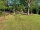 Well-maintained backyard, featuring mature trees providing ample shade and a partial fence at 566 Huff St, Lawrenceville, GA 30046
