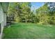 Wide view of the home's lush green backyard with surrounding trees, wooden deck and brick exterior at 3150 Stonewall Tell Rd, Atlanta, GA 30349
