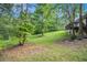 Lush backyard featuring a sloped lawn, mature trees, and a glimpse of the home's exterior at 3150 Stonewall Tell Rd, Atlanta, GA 30349