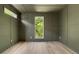 A modern bedroom featuring wood floors and an olive color scheme is bathed in natural light from a window at 644 Glendale Rd, Scottdale, GA 30079