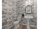 Charming powder room features patterned wallpaper, pedestal sink, and updated fixtures at 5604 Mccullers Ln, Loganville, GA 30052