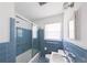 Updated bathroom features blue tile, shower-tub, and bright lighting at 2685 Buena Vista Ave, Doraville, GA 30340