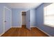 Bedroom with blue walls, wood floors, a window with blinds, and closet with open door at 2685 Buena Vista Ave, Doraville, GA 30340