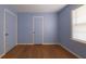 Bedroom with blue walls, wood floors, a window with blinds, and two white doors at 2685 Buena Vista Ave, Doraville, GA 30340
