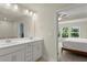 Bathroom with double sink vanity, white cabinets, large mirror, and view to bedroom with light and windows at 350 Hayden Cir, Woodstock, GA 30189