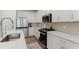 Close-up of a bright kitchen featuring white cabinets, stainless steel appliances, and hardwood floors at 350 Hayden Cir, Woodstock, GA 30189