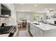 Open-concept kitchen featuring white cabinets, stainless steel appliances, a center island, and views into the living area at 350 Hayden Cir, Woodstock, GA 30189