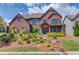 Stunning brick home featuring manicured landscaping, stone steps and charming architectural details on a sunny day at 2631 Moon Chase Lane, Buford, GA 30519