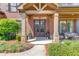 Inviting front porch with stone columns, wood detailing, comfortable seating, and lush landscaping at 2631 Moon Chase Lane, Buford, GA 30519