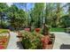 Lush backyard featuring a manicured lawn, vibrant flowering shrubs, a sidewalk, mature trees, and greenery all around the home at 2920 Dara Dr, Marietta, GA 30066