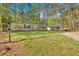 Single-story home with a well-maintained lawn and a long driveway, surrounded by lush trees at 5400 Kings Camp Cabin 16 Se Rd, Acworth, GA 30102