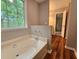 Bathroom featuring a soaking tub by a window and wood flooring, creating a spa-like atmosphere at 14 Highland Dr, Carrollton, GA 30116