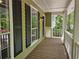 Covered porch with wood decking, offering a welcoming entrance and views of the surrounding greenery at 14 Highland Dr, Carrollton, GA 30116