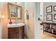 Stylish powder room featuring a decorative mirror, dark wood vanity, and views into other rooms at 1872 Lake Lucerne Sw Dr, Lilburn, GA 30047