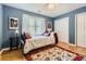 Cozy bedroom featuring blue walls, light hardwood floors, a ceiling fan, and a large window with natural light at 1872 Lake Lucerne Sw Dr, Lilburn, GA 30047
