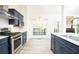 Open concept kitchen features stainless steel appliances, navy cabinets, quartz countertops, and wood floors at 4080 Birch Bark Way, Douglasville, GA 30135