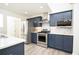 Close up of the kitchen featuring stainless steel appliances, marble backsplash, and navy blue cabinets at 4080 Birch Bark Way, Douglasville, GA 30135