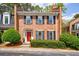 Charming brick townhome featuring a red front door, black shutters, and manicured landscaping at 12 Valley Forge Nw Pl # 215, Atlanta, GA 30318