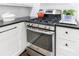 Modern stainless steel range top with matching oven and black countertops; tiled backsplash at 12 Valley Forge Nw Pl # 215, Atlanta, GA 30318